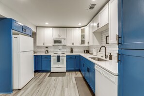 A modern kitchen with white and blue cabinets, a microwave, stove, sink, and dishwasher. - 8 Mi to Nissan Stadium & Broadway! (Nashville)