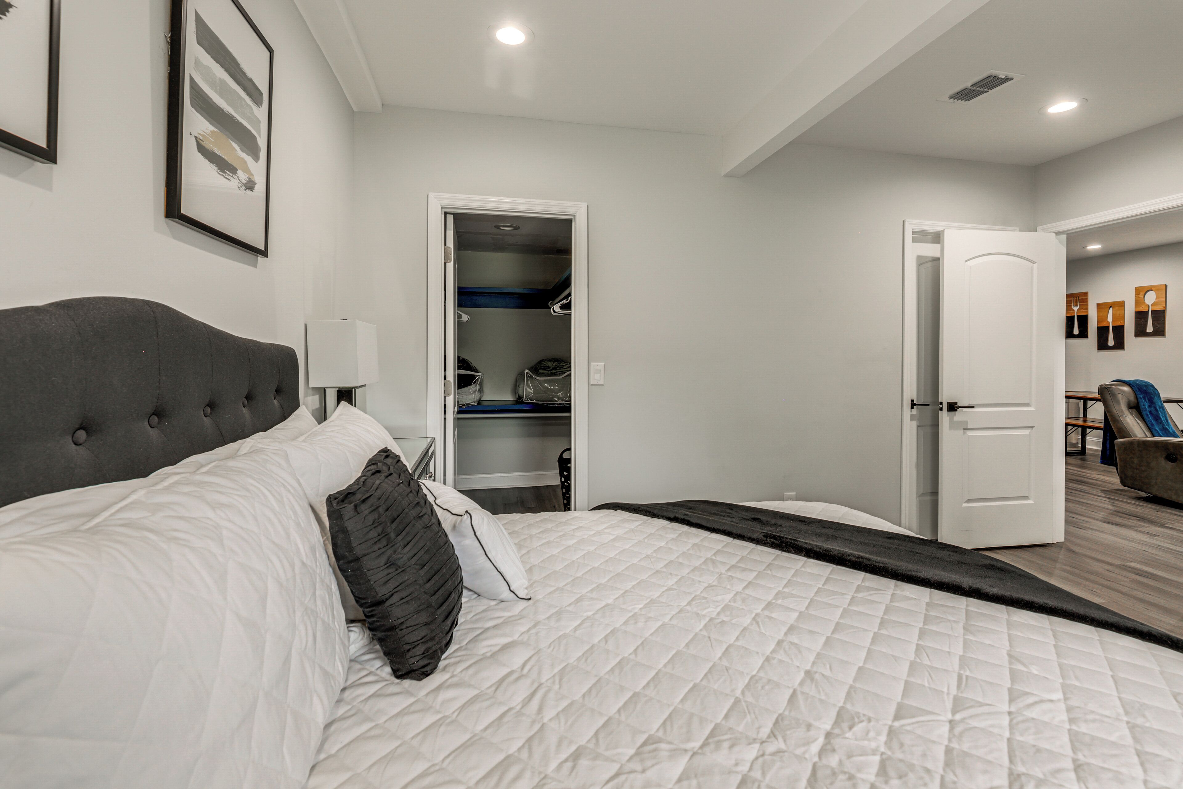 A bedroom with a bed, a bedside table, a lamp, a closet, and a door leading to another room. - 8 Mi to Nissan Stadium & Broadway! (Nashville)