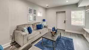 A modern living room with a grey sofa, blue cushions, a coffee table, and a blue rug. - 8 Mi to Nissan Stadium & Broadway! (Nashville)