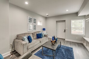 A modern living room with a grey sofa, blue cushions, a coffee table, and a blue rug. - 8 Mi to Nissan Stadium & Broadway! (Nashville)