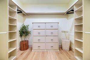 A walk-in closet with open shelves, a white chest of drawers, a wicker basket, and a laundry basket. - Lake Views, Big Deck, Hot Tub, Fire Pit, Game Room (Park Hill)