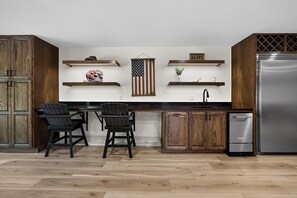 Eine Küche mit Holzschränken, einem Edelstahlkühlschrank und zwei Barhocker.