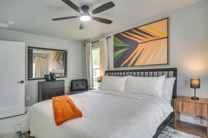 A bedroom with a bed, a ceiling fan, a nightstand, a chair, a dresser, and a large abstract painting. - Sleek & Central! Safety Harbor Home Near Beaches (Safety Harbor)