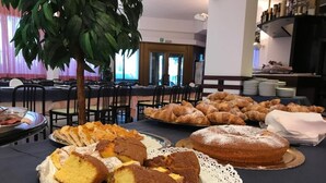 A buffet table with various desserts including cakes and pastries.