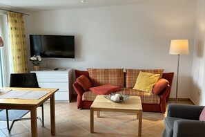 Una habitació moblada amb sofà, taula, televisió i làmpada.