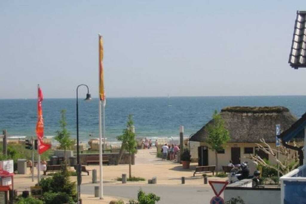 Eine Küstenstadt mit Strand, einem Gebäude mit Strohdach und einer Fahnenmast.