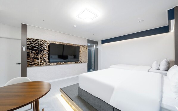 Una habitación de hotel moderna con una cama, un escritorio y un televisor montado en la pared.