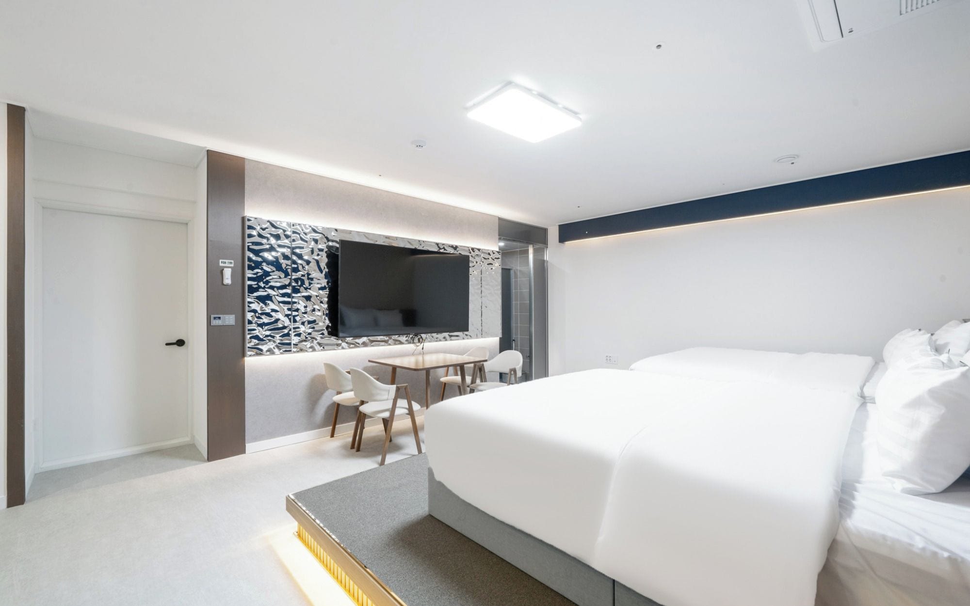 Una habitación de hotel moderna con una cama grande, un escritorio con una silla, un televisor y zona de ducha.
