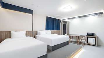 Habitación de hotel con dos camas, un escritorio, un microondas y una pequeña zona de estar.