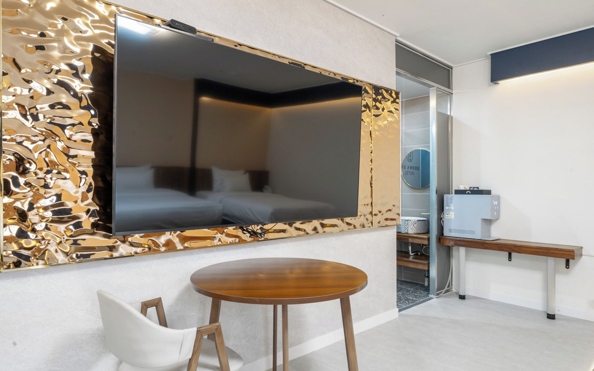 A hotel room with a bed, a large mirror, a wooden table, and a chair.