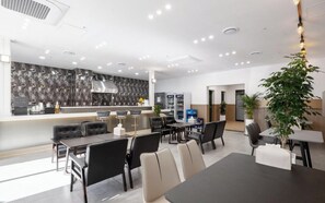 Et moderne spiseområde med kaffebar, siddepladser og en dekorativ væg.