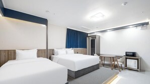 Una camera d'albergo con due letti, una scrivania, una sedia, un forno a microonde e un minibar.