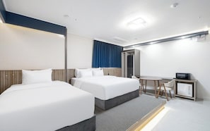 Et hotelværelse med to senge, et skrivebord, en stol, en mikrobølgeovn og minibar.