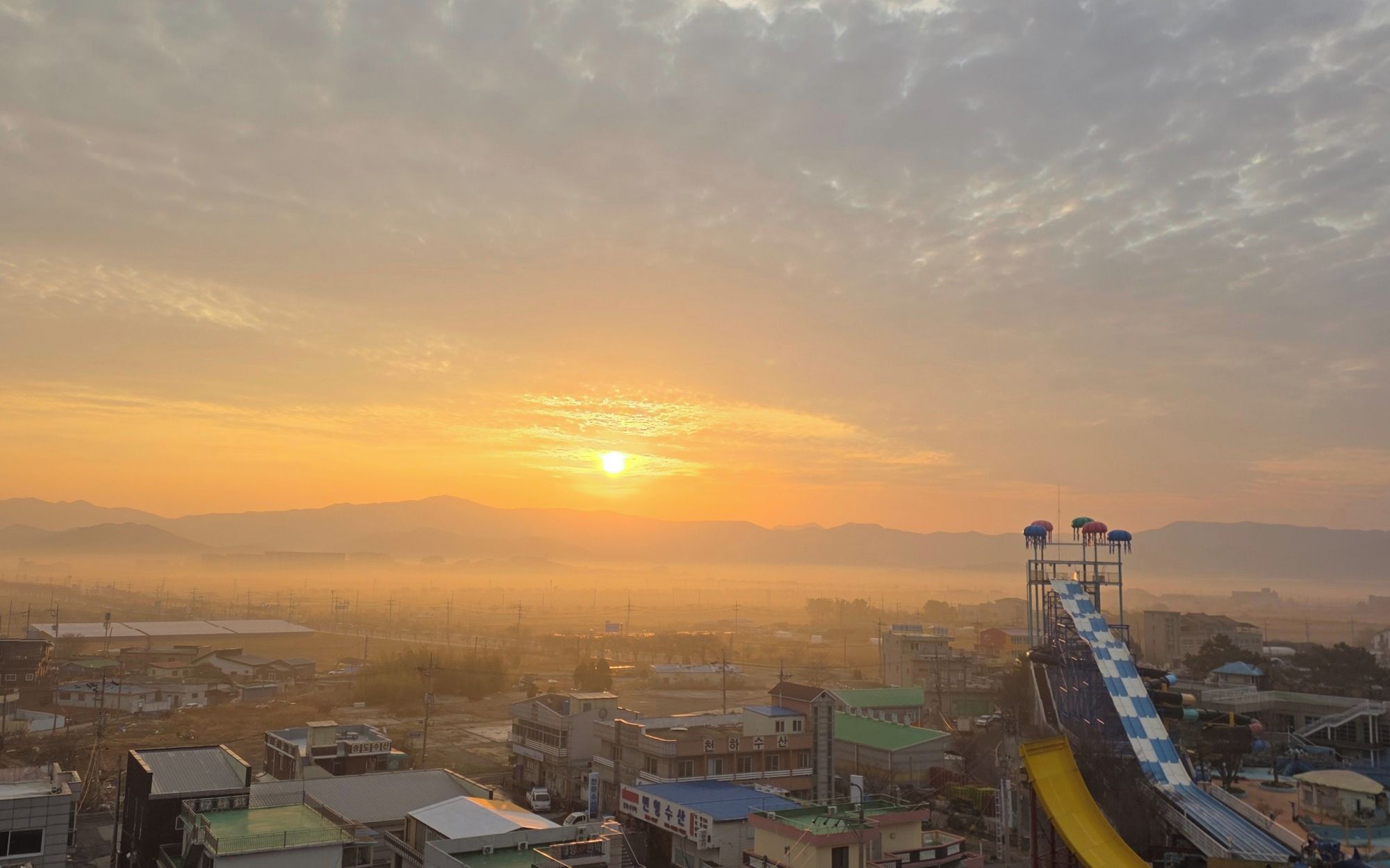 A cityscape with a water slide at sunset.