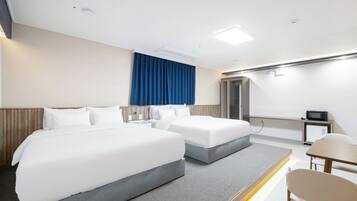 Una habitación de hotel con dos camas, un escritorio, una silla, un microondas y una puerta.