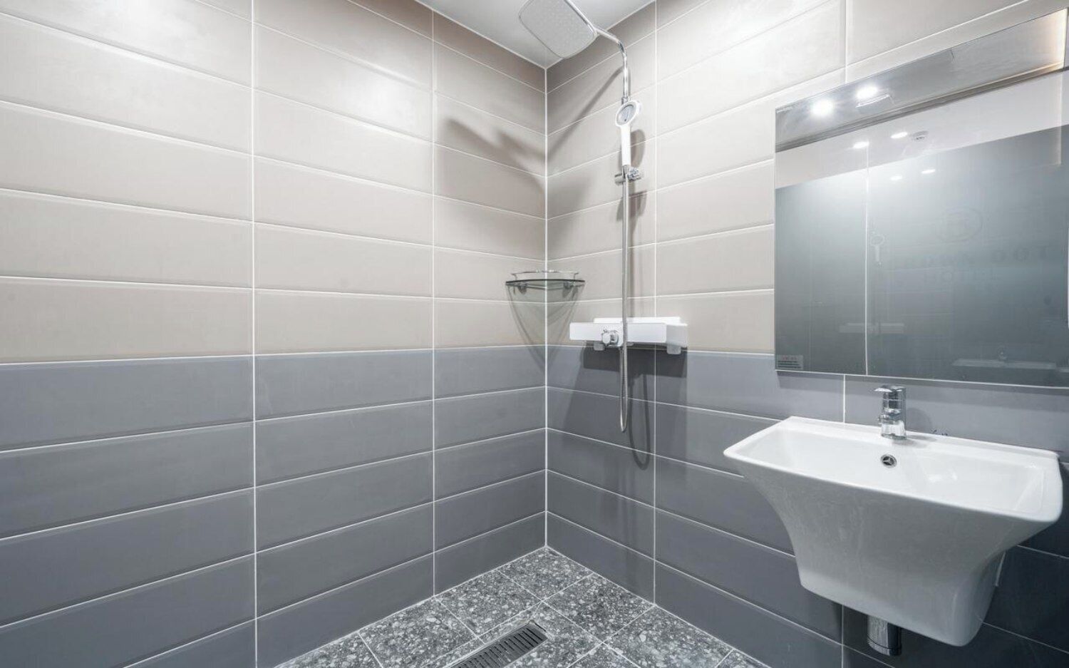 A modern bathroom with grey tiles, a shower, and a sink.