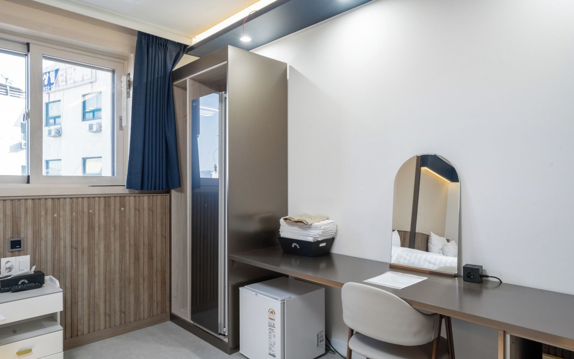 Quarto moderno com escrivaninha, cadeira e mini-geladeira.