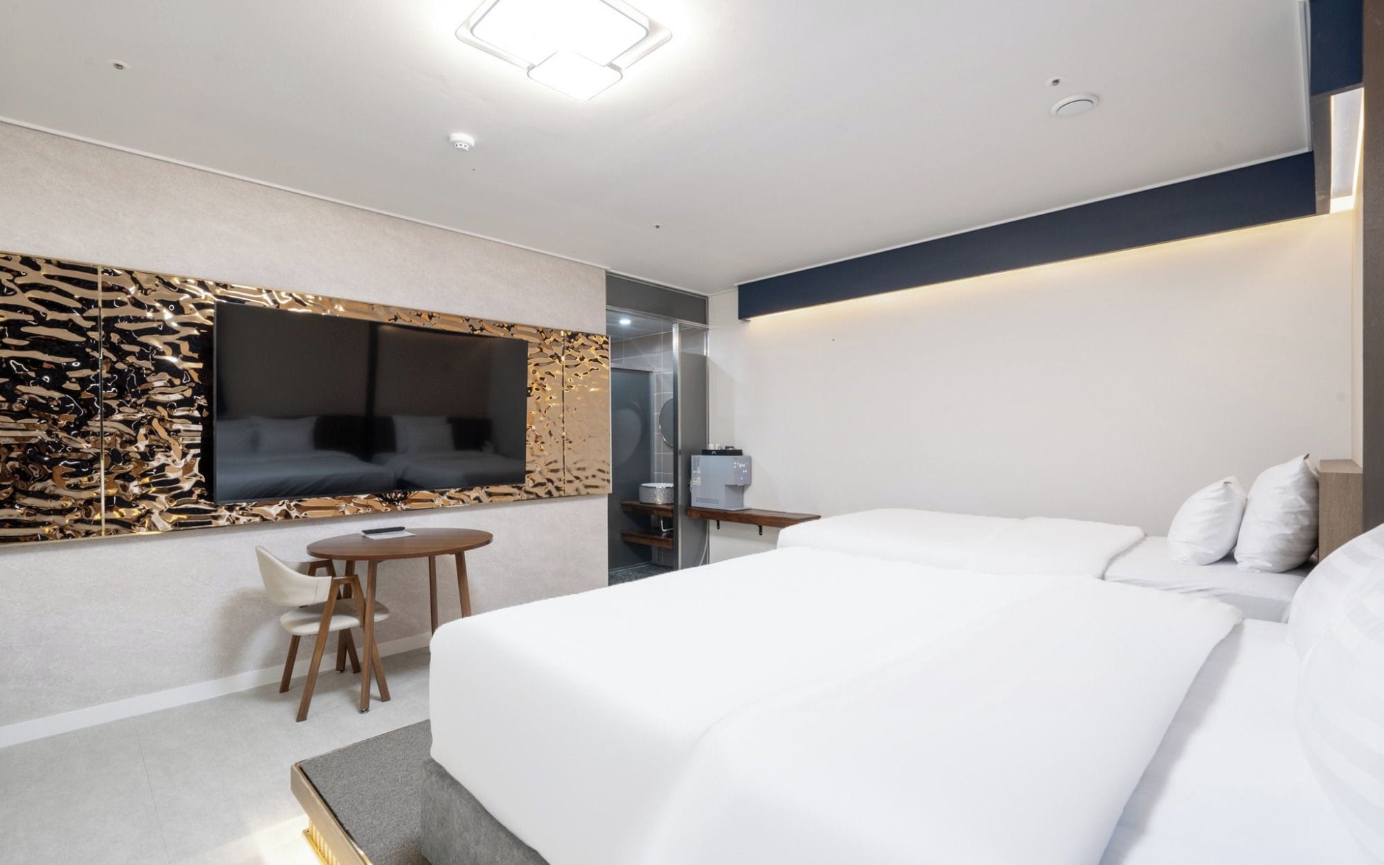 A hotel room with a bed, a TV mounted on the wall, a small table, and a chair.