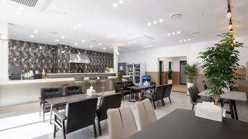 A modern dining area with a coffee bar, bar stools, and a large potted plant.