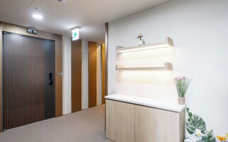 A hotel reception area with a reception desk, a wooden door, and a wall-mounted light fixture.