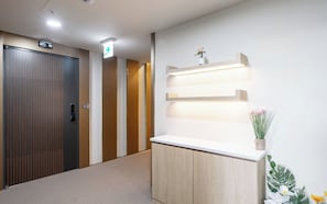 A hotel reception area with a reception desk, a wooden door, and a wall-mounted light fixture.