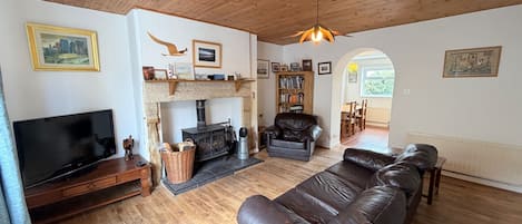 A cozy living room with a fireplace, leather sofa, television, and wooden flooring.