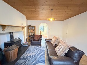 A cozy living room with a fireplace, leather sofa, and a bookshelf. - Spahome's By The Sea (Morpeth)