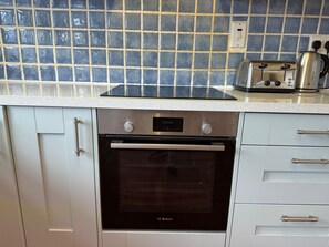 A kitchen with a Bosch oven, a toaster, and a tiled backsplash. - Spahome's By The Sea (Morpeth)