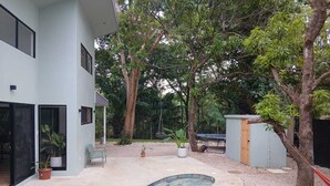 Ein modernes Haus mit Schwimmbecken, umgeben von Bäumen und einem Kiesbereich.