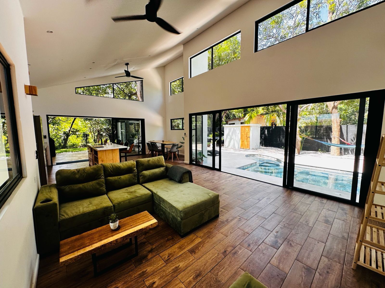 A spacious living area with a sectional sofa, a wooden coffee table, and a ceiling fan.