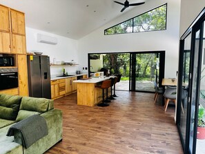 Una cocina moderna con armarios de madera, horno empotrado y una isla grande con taburetes de bar.