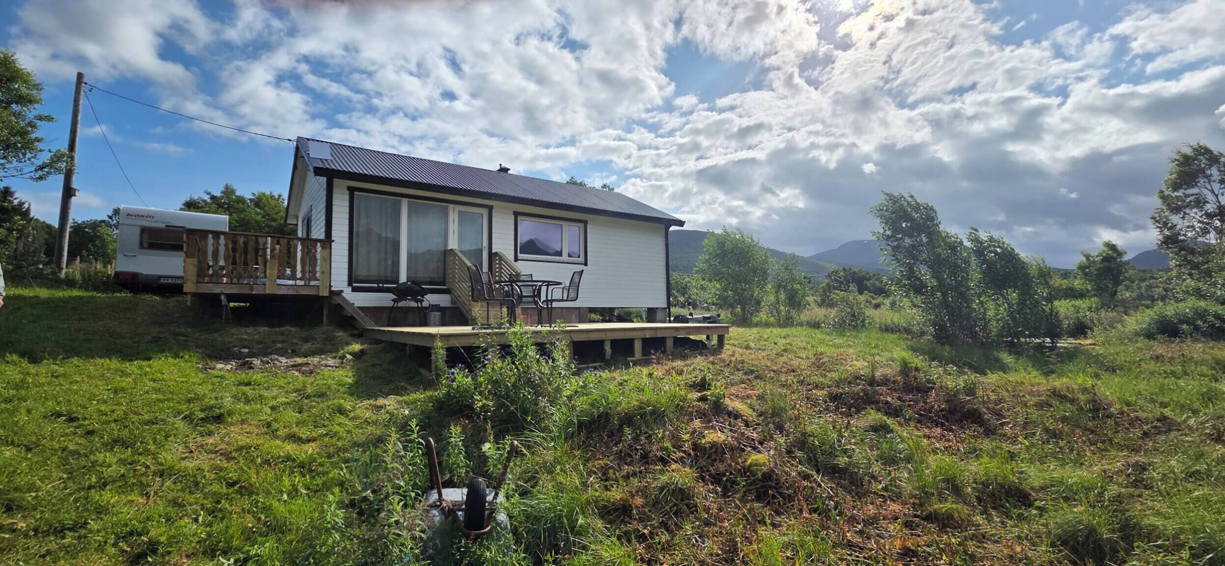 Ein eingeschossiges Haus mit einer Terrasse, einer überdachten Sitzgruppe und Blick auf die Berge.