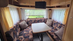 A cozy RV interior with a sofa set, a table, and curtains.