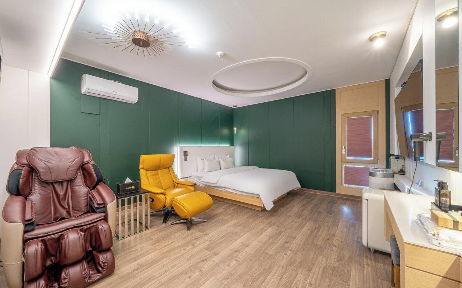 Habitación de hotel con cama, sillón de masajes, una mesita y un espejo.