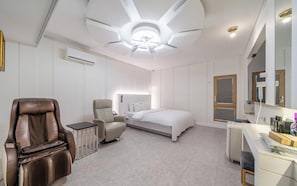 Una habitación de hotel con cama, sillón de masaje, escritorio y un espejo grande.