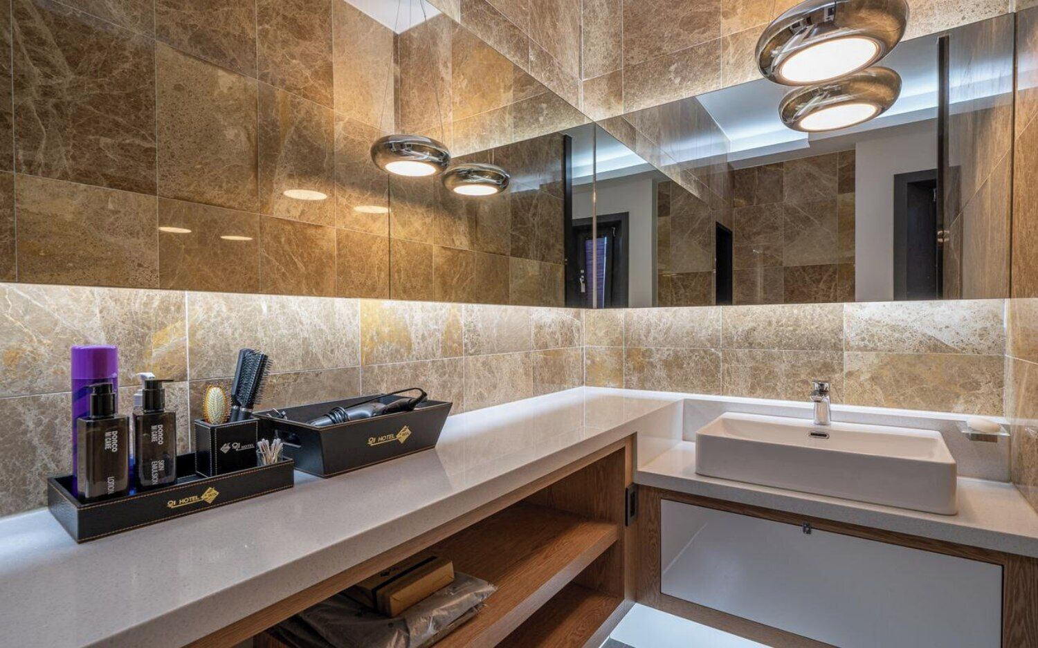 A modern bathroom with marble walls, a vanity with a sink, and a mirror.