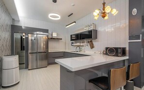 Una cocina moderna con electrodomésticos de acero inoxidable, una isla central y una araña.