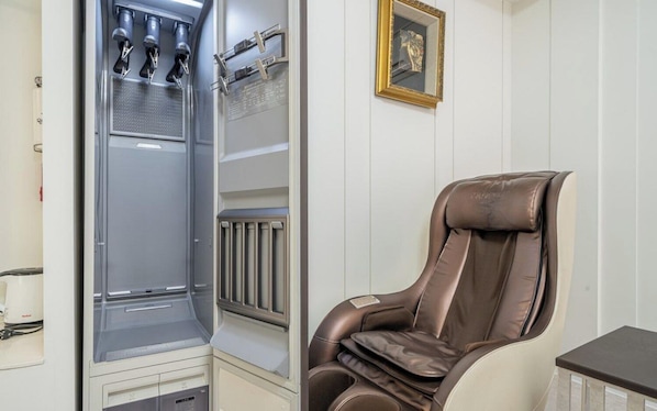 Una silla de masaje en una habitación con pared blanca y un radiador.