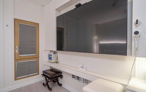 A room with a large mirror, a wooden door with a window, a small table, and a white bench. - Andong Win Hotel (Andong)