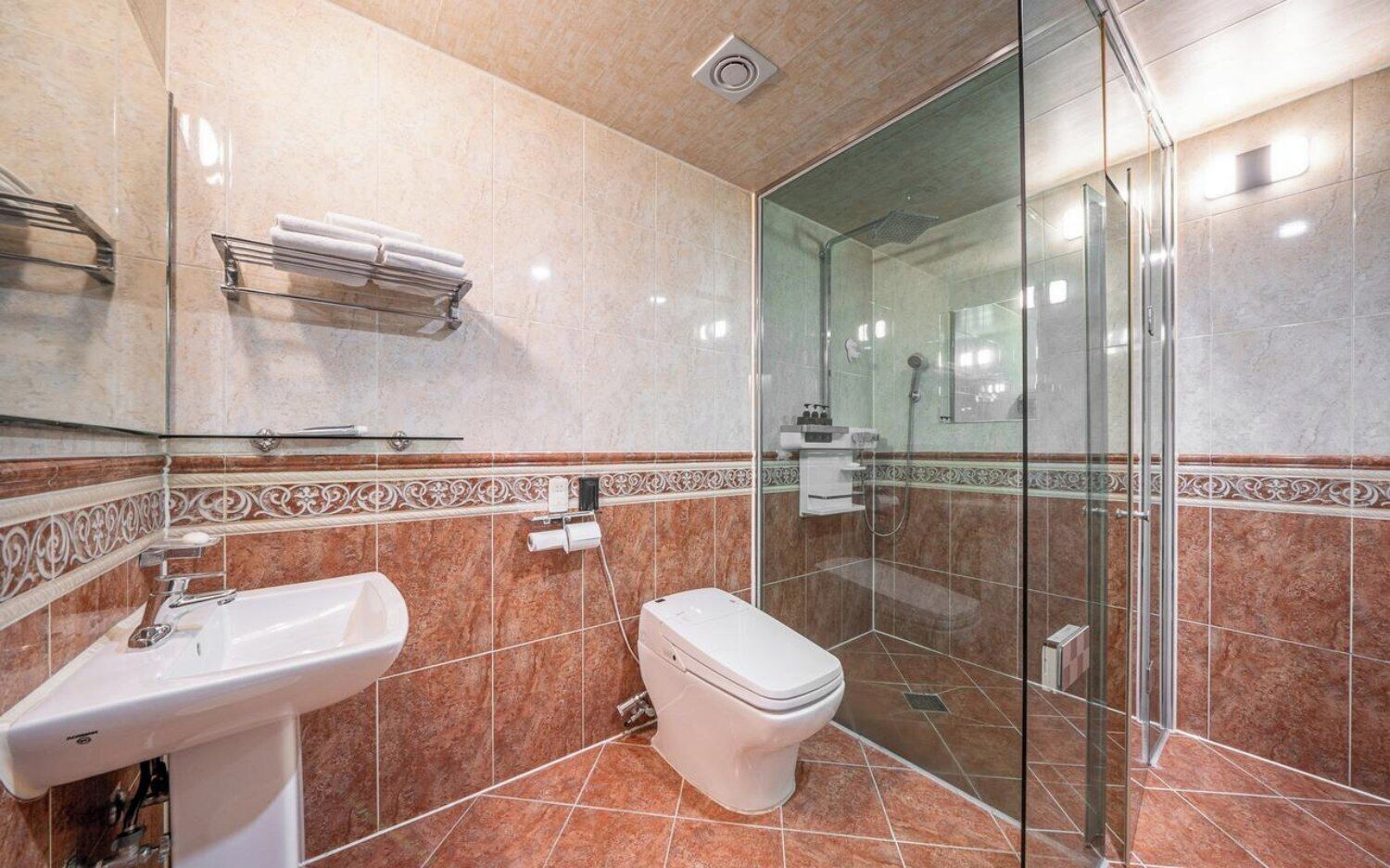A bathroom with a glass-enclosed shower, a sink, and a toilet.
