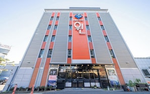 Un edificio de hotel con un llamativo letrero 'HOTEL', la entrada de una cafetería y el logotipo 'WIN'.