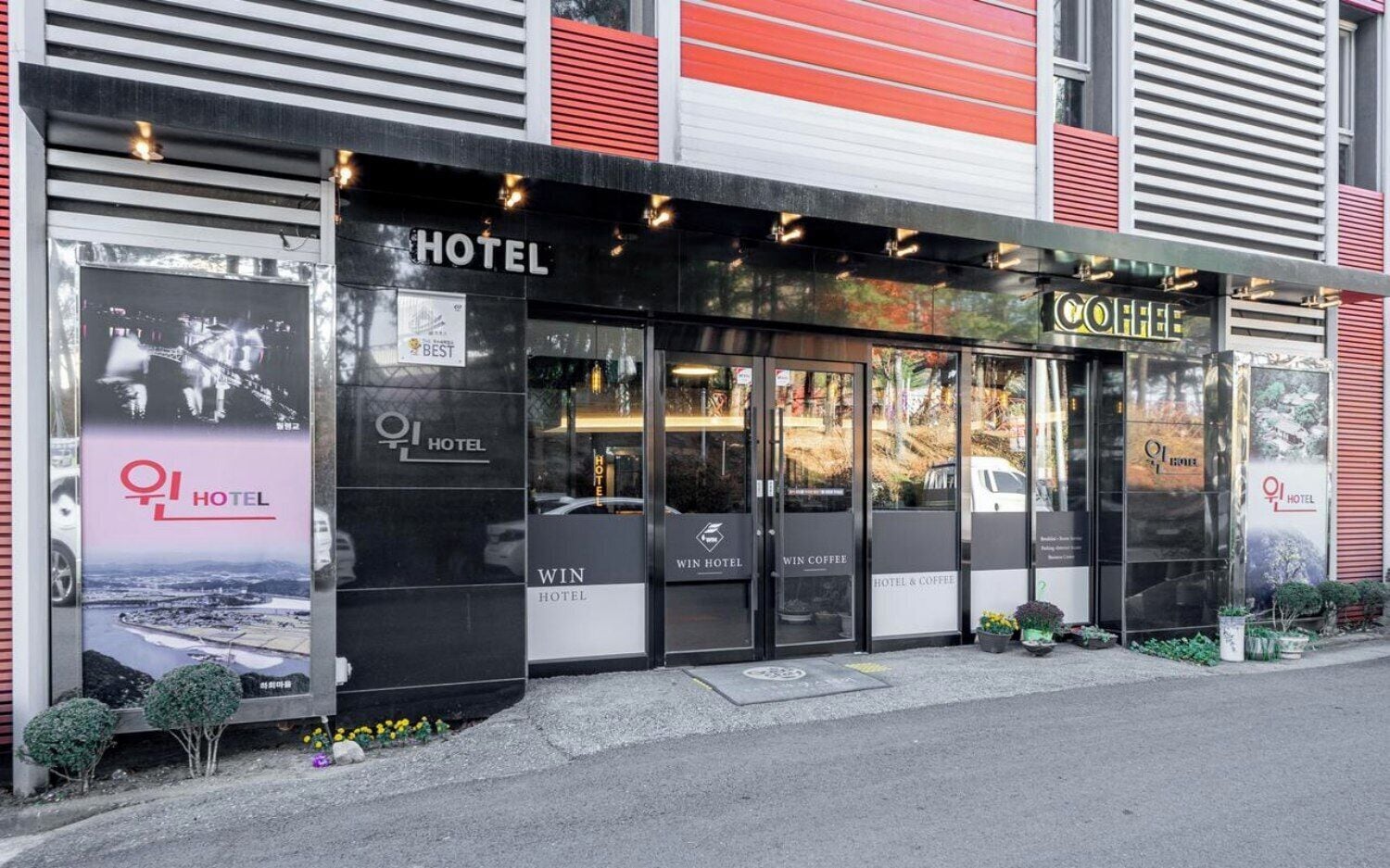 Un hotel con un letrero grande que dice 'HOTEL', un letrero que dice 'WIN HOTEL' y un letrero que dice 'WIN COFFEE'.