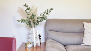 Una sala de estar con un sofá gris, una mesita de madera con un florero y un cuadro en la pared.