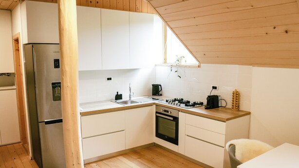 Una cocina moderna con armarios blancos, un refrigerador de acero inoxidable, una estufa a gas y un lavamanos.