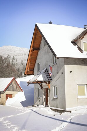 Un edificio a due piani con tetto spiovente, un portico in legno e una piccola finestra.