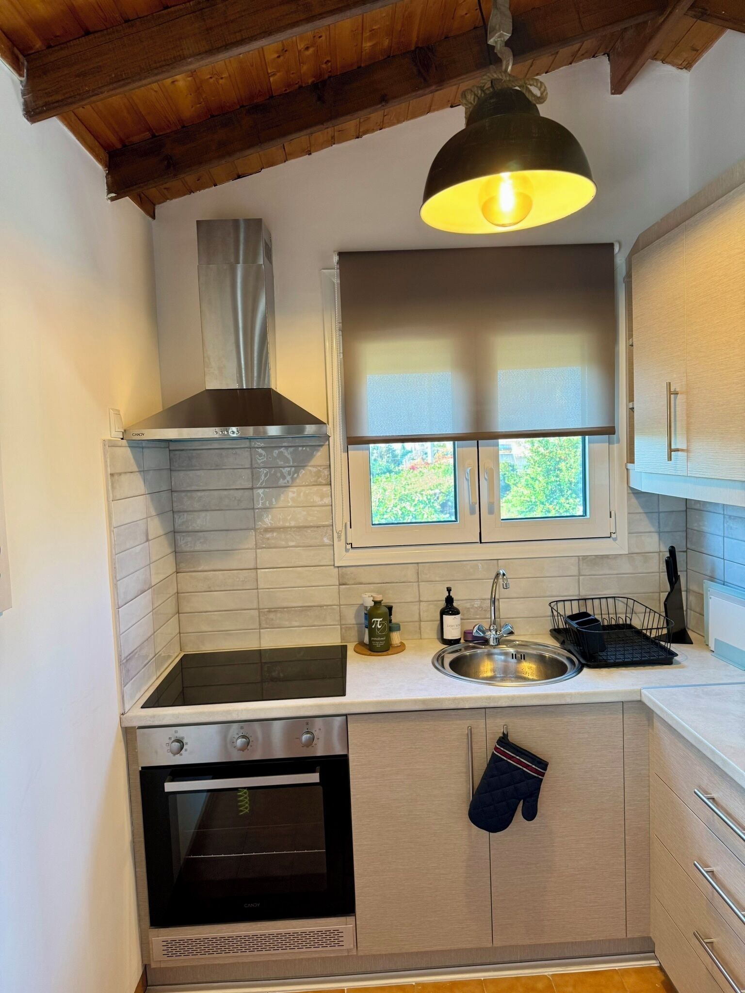 A compact kitchen with a stove, oven, and a window above the sink.