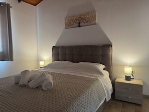 Un dormitorio con una cama grande, dos lámparas de noche, una mesita de noche y una obra de arte colgada en la pared.