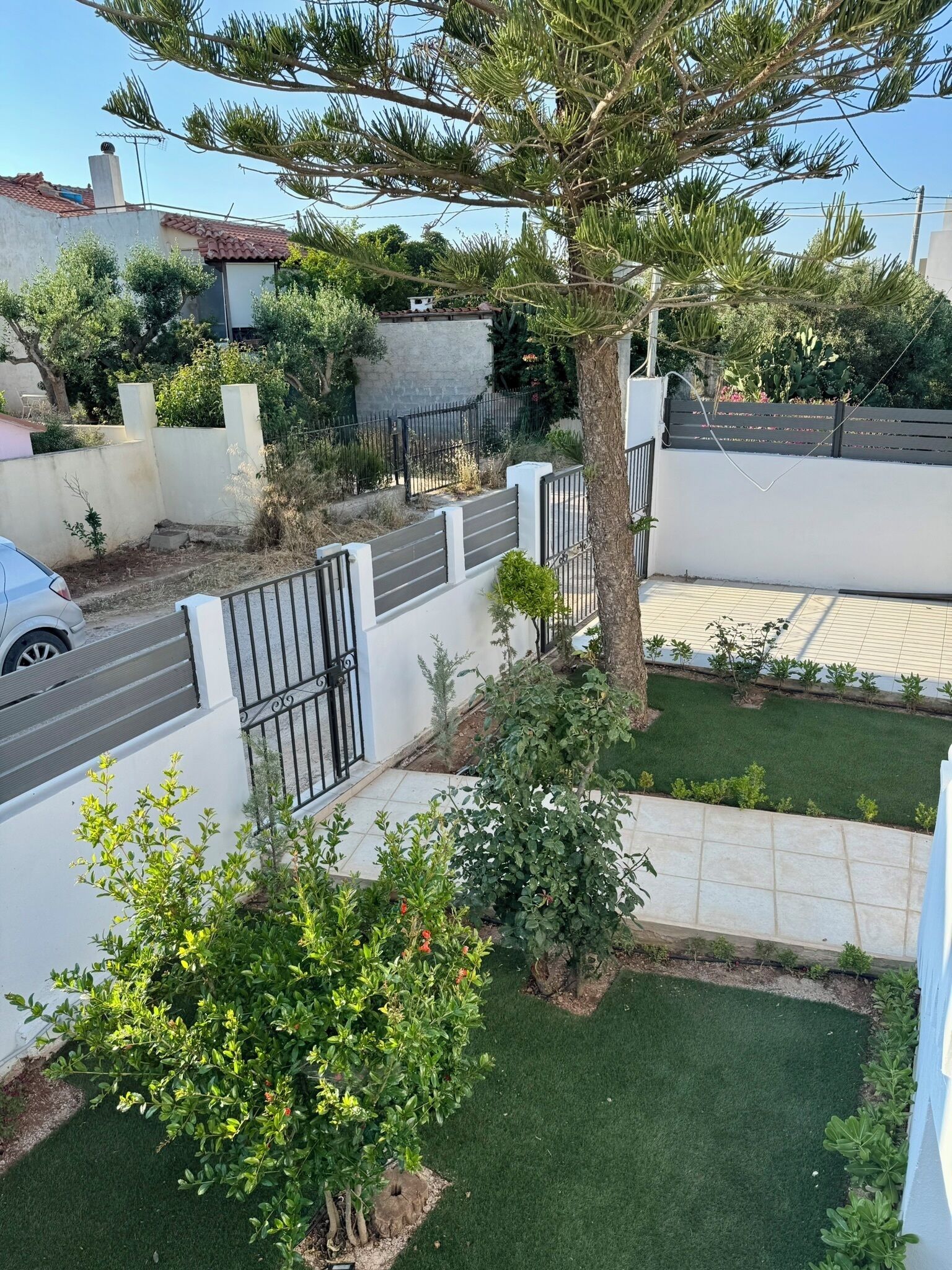 A residential area with a white building, a tree, and a paved driveway.