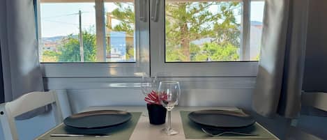 Een eettafel gedekt met twee borden, een wijnglas en een potplant.