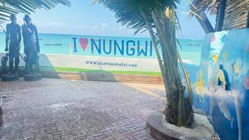 Vista de la playa con un cartel que dice 'I ♥ NUNGWI' y una dirección web.